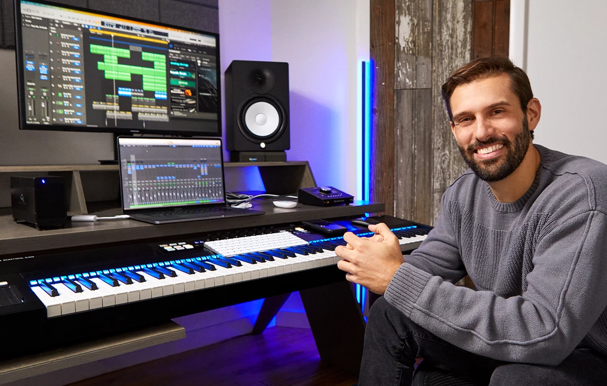 Ryan Nach sitting in front of a computer with a music production software and a keyboard