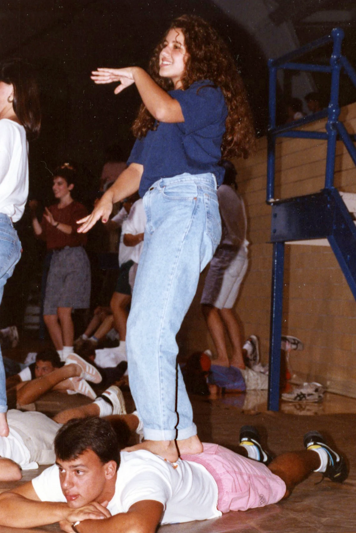 men laying on the ground on their stomaches while women stand on their backs like a surfboard