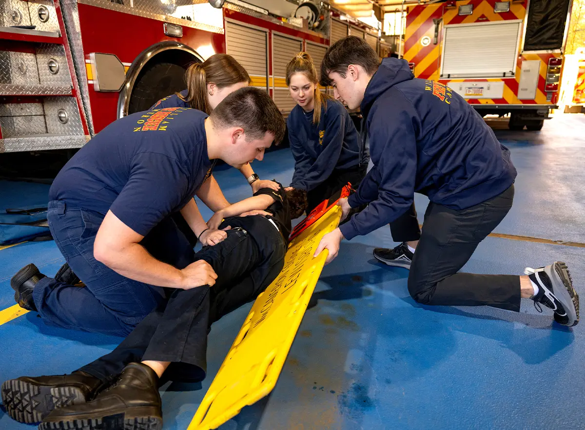 students perform a log roll during a spinal immobilization exercise in a fire station