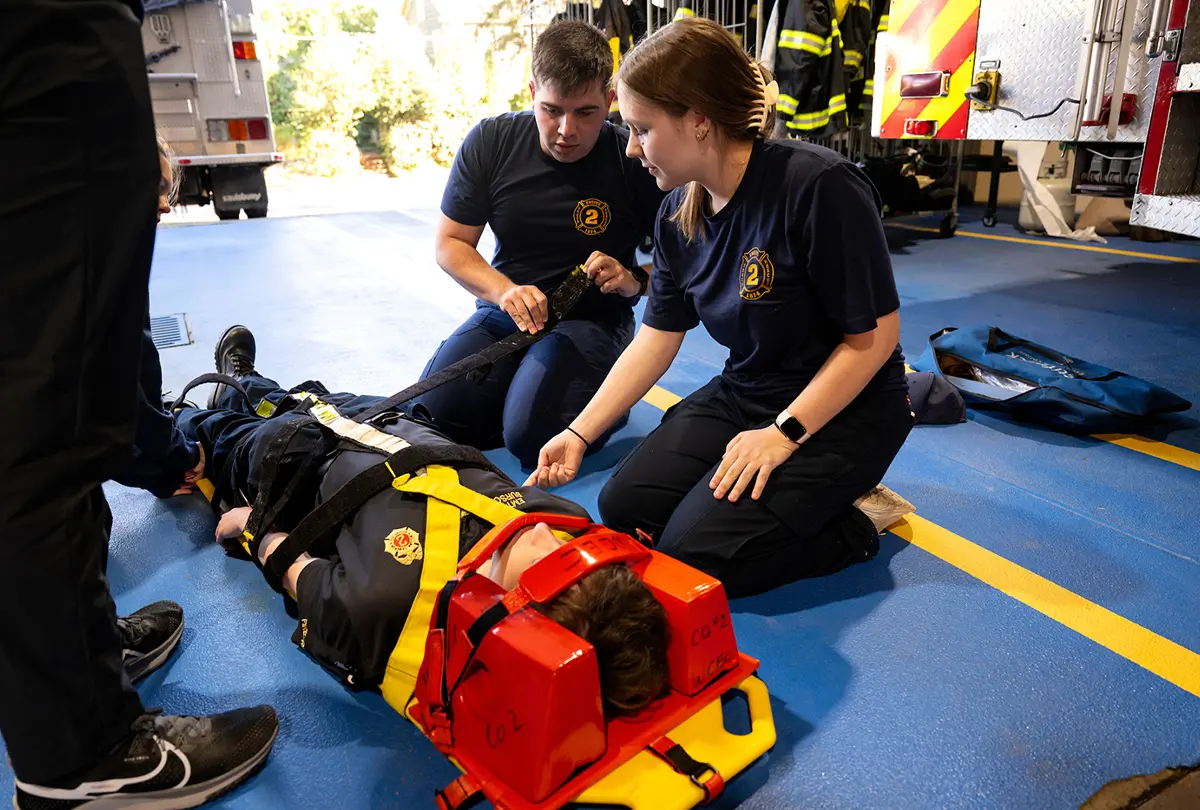 students secure the patient during a spinal immobilization exercise in a fire station