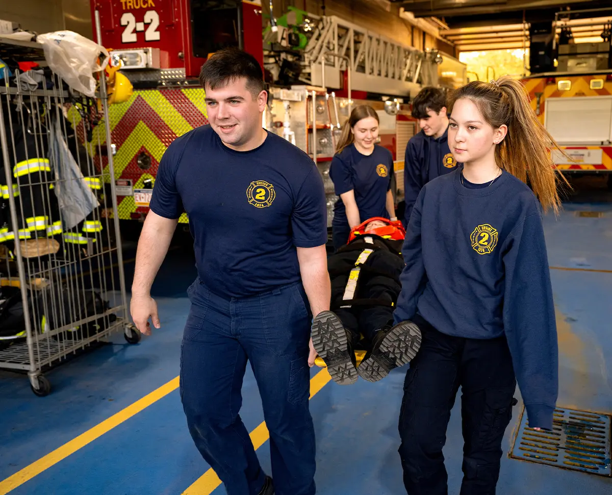 with two holding the leg end and two holding the head end of the back board students perform the patient extrication process during a spinal immobilization exercise