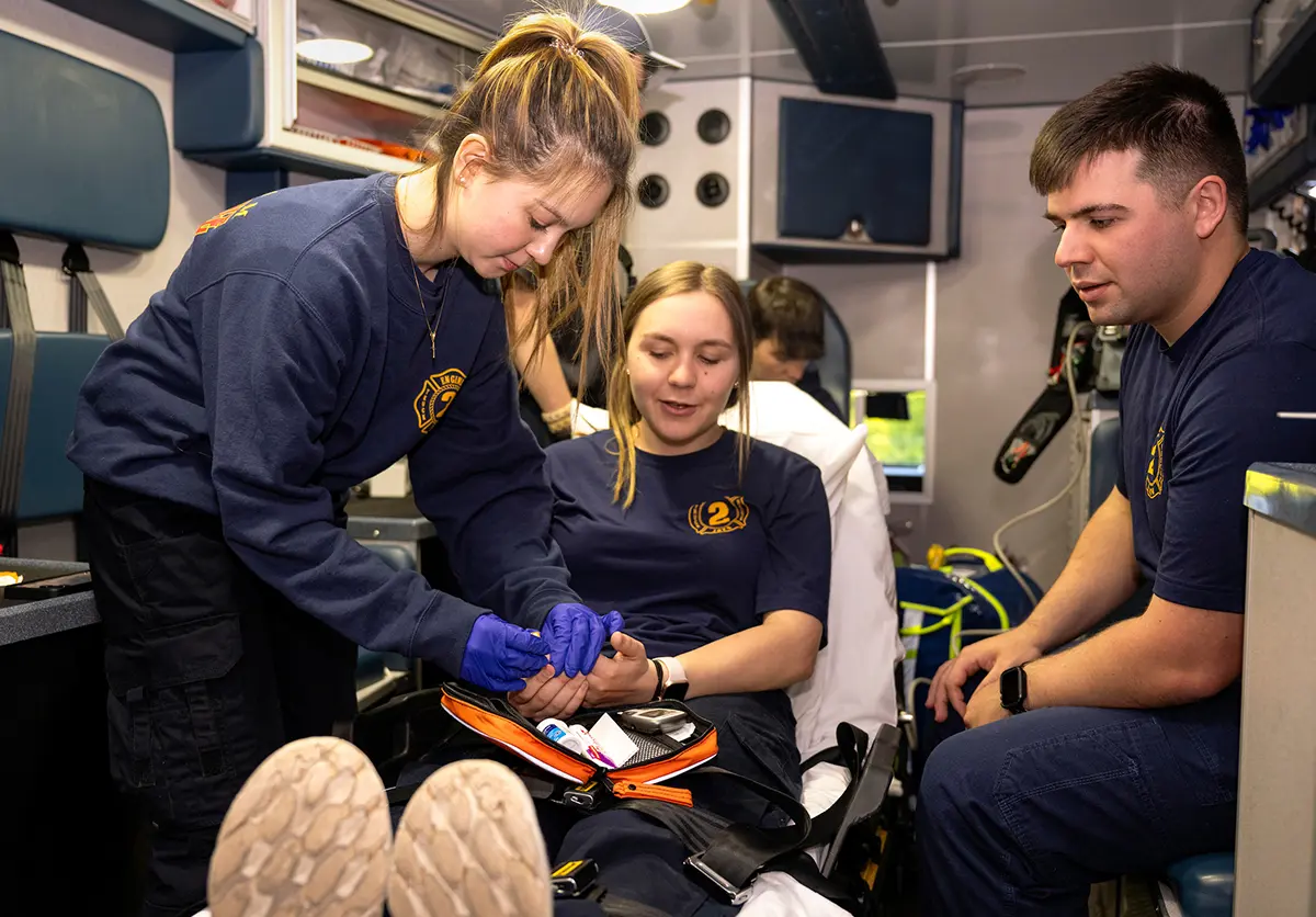 Kathryn Wrynn ’26, Olivia Jaye ’26, Matt Otto ’24, and William Burson ’26 perform an exercise while in the back of an EMS vehicle