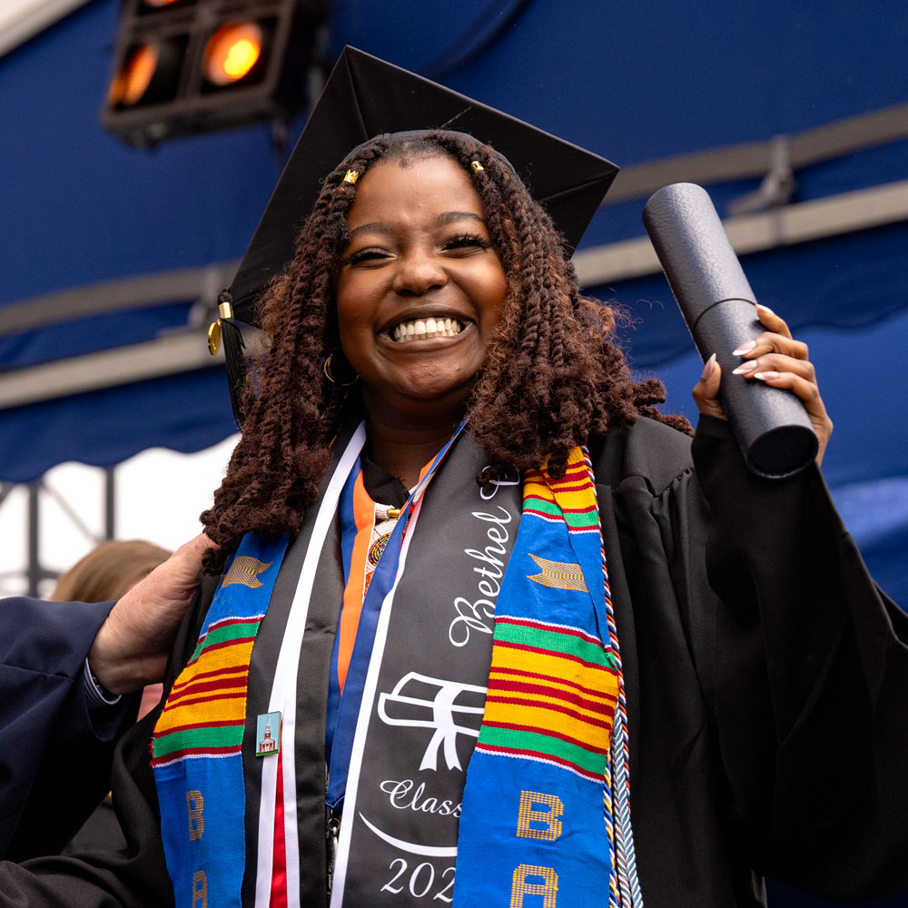 student smiling on stage after receiving her college degree during graduation ceremony