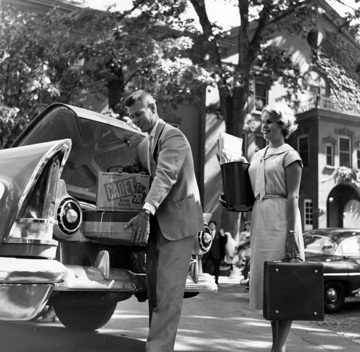 vintage black and white photo of man and woman packing car trunk with luggage