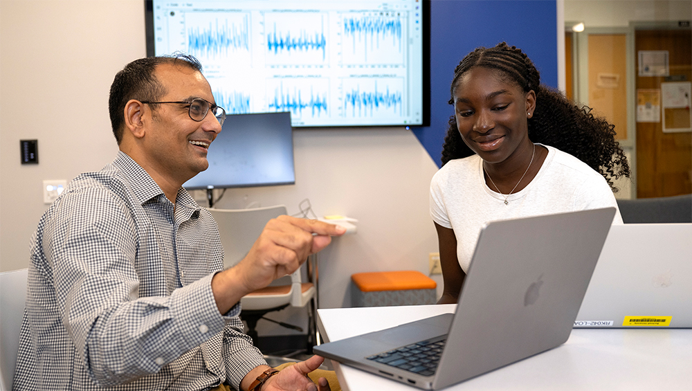professor pointing something out on a laptop to a student