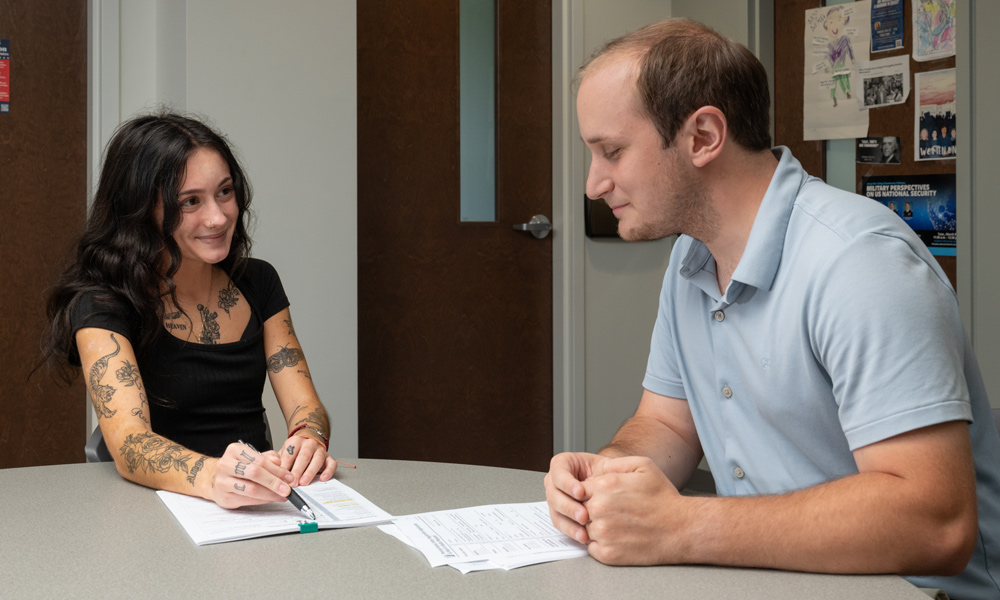 Morgan Levy and Zane Hensal sitting together a table with paperwork between them