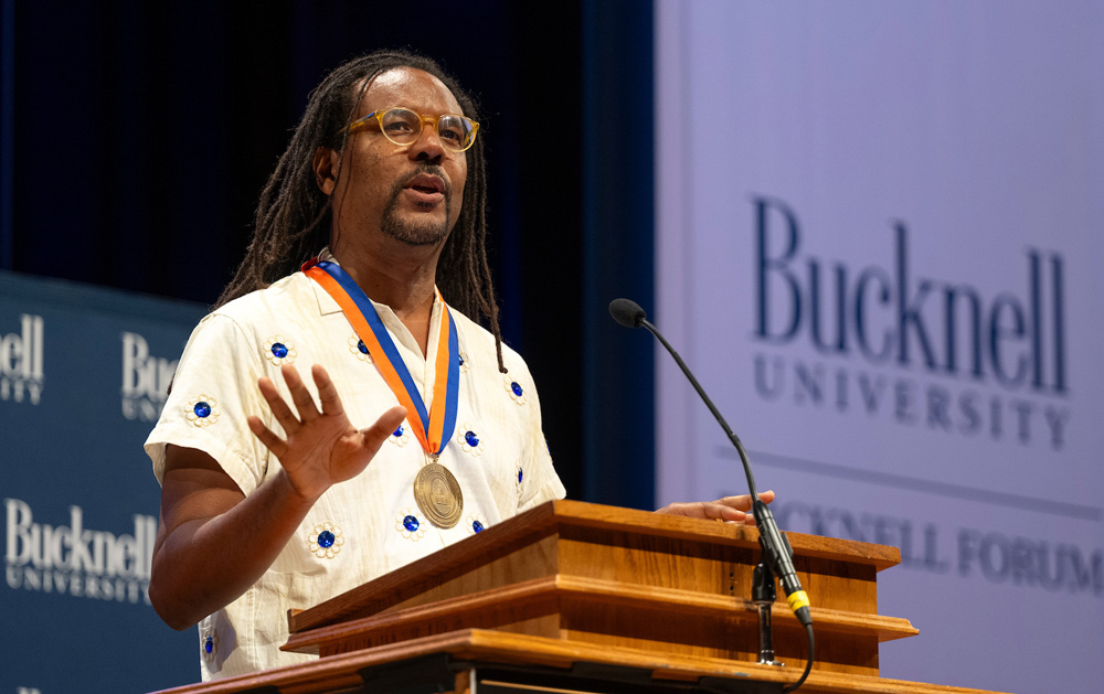 Colson Whitehead speaking at podium while wearing medal