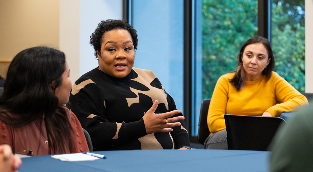 Yamiche Alcinor seated at a table speaking to those around her