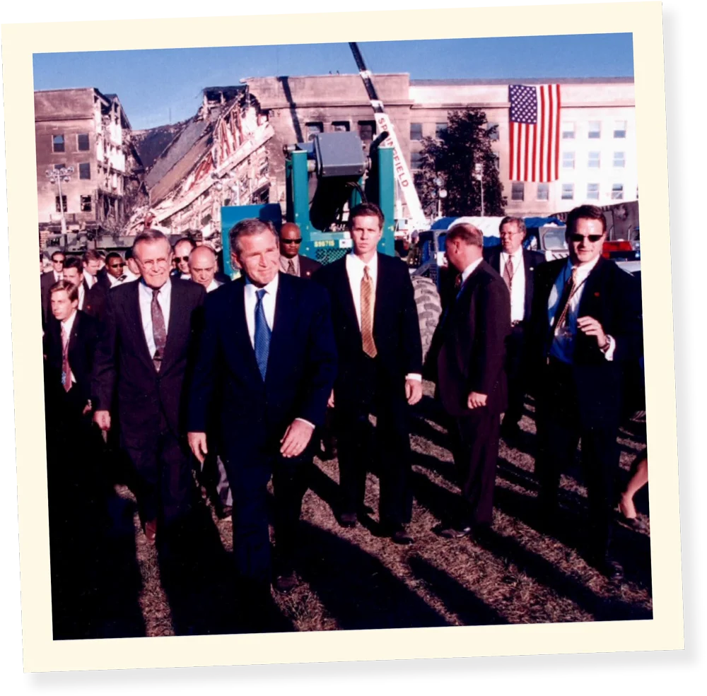President George W. Bush and then-Secretary of Defense Donald Rumsfeld survey the damage of the Pentagon building after 9/11 alongside a young Carl Agnelli (far right), who is clad in the prototypical black sunglasses