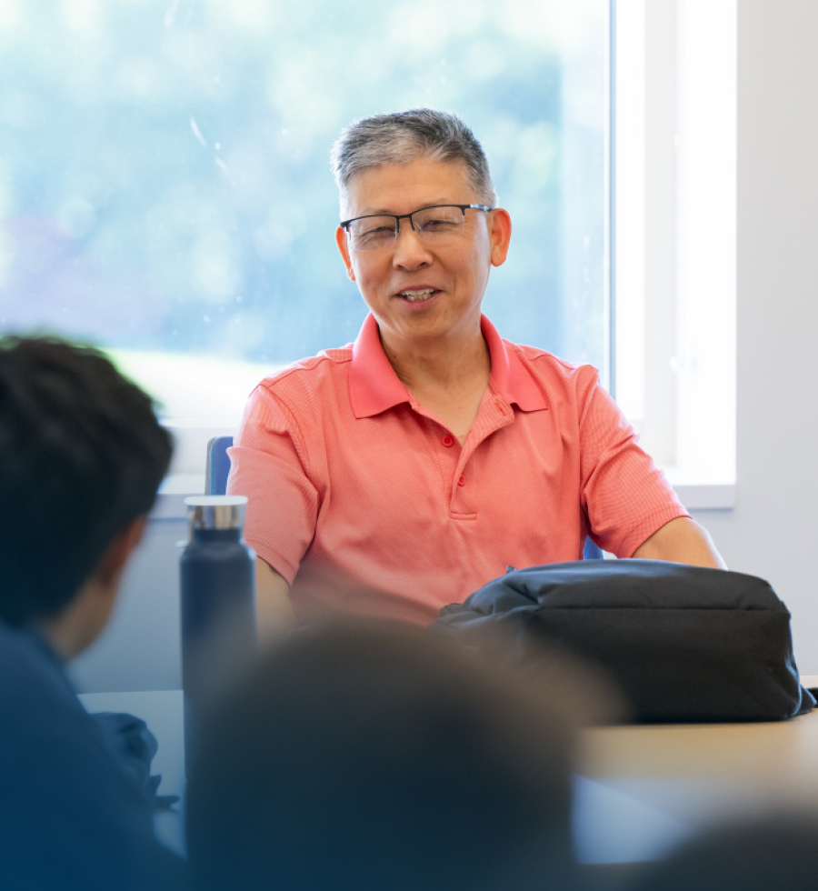 professor Zhiqun Zhu sitting at table speaking to students