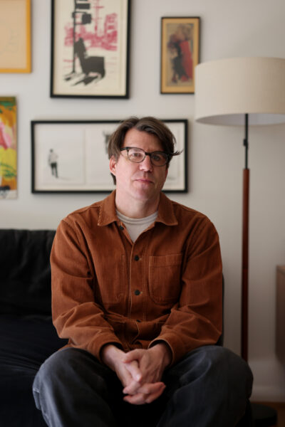 A photo of the author Kevin Moffett sitting on a couch and staring forward.