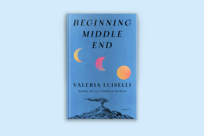 A book cover appears on a pale blue background. The book&rsquo;s title, Beginning Middle End, appears in a black serif font at the top. Phases of the moon in pink and yellow are in the middle. The author&rsquo;s name, Valeria Luiselli, appears near the bottom, above an illustration of an erupting volcano.
