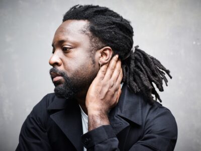 A portrait of the author Marlon James looking to his right with his left hand along his neck.