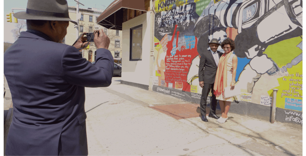 Color photograph of a couple on easter being photographed by a third individual.