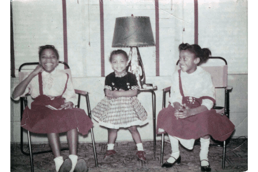 A color photograph of three young girls at home.