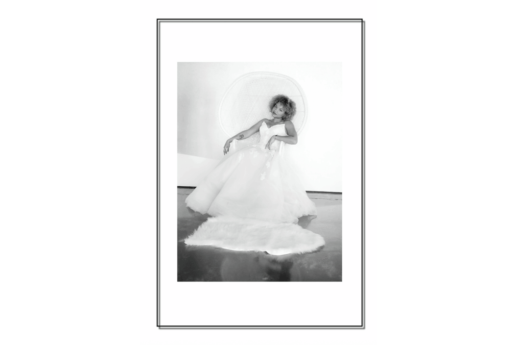 A woman in a bridal gown sitting on a chair.