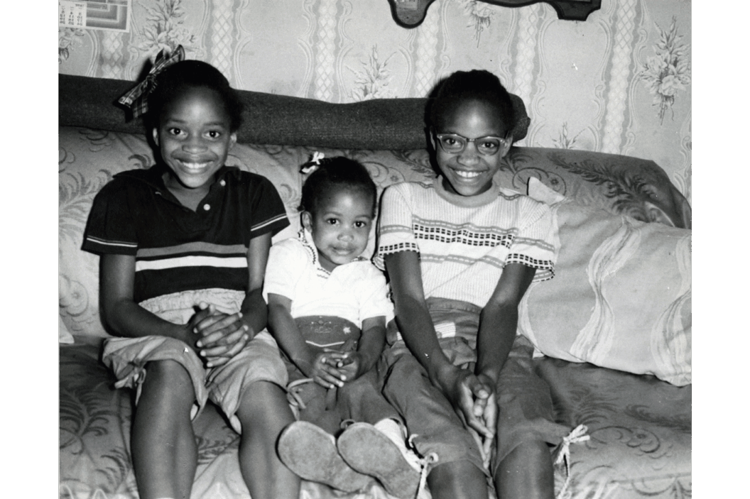 A black-and-white photograph of three young girls on a couch.