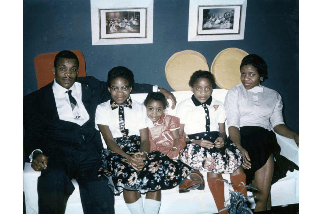 A color photograph of a family of five at home.