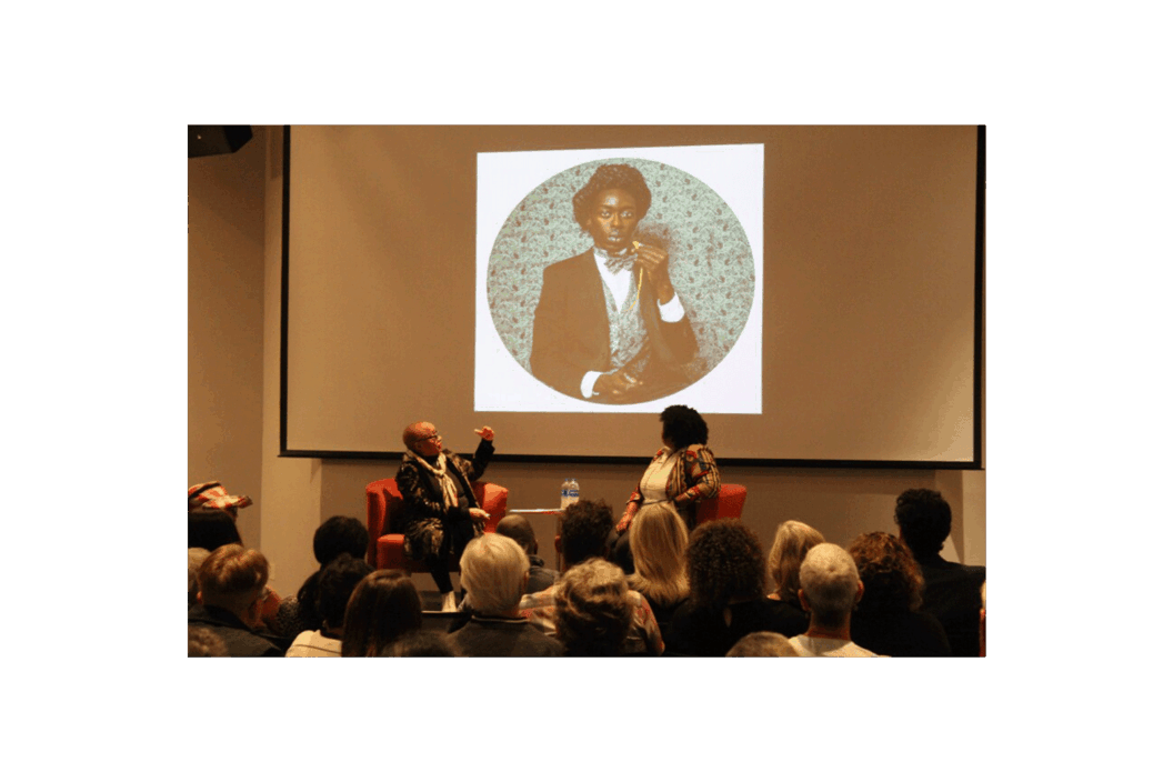 Color photograph of the artist at a public talk.