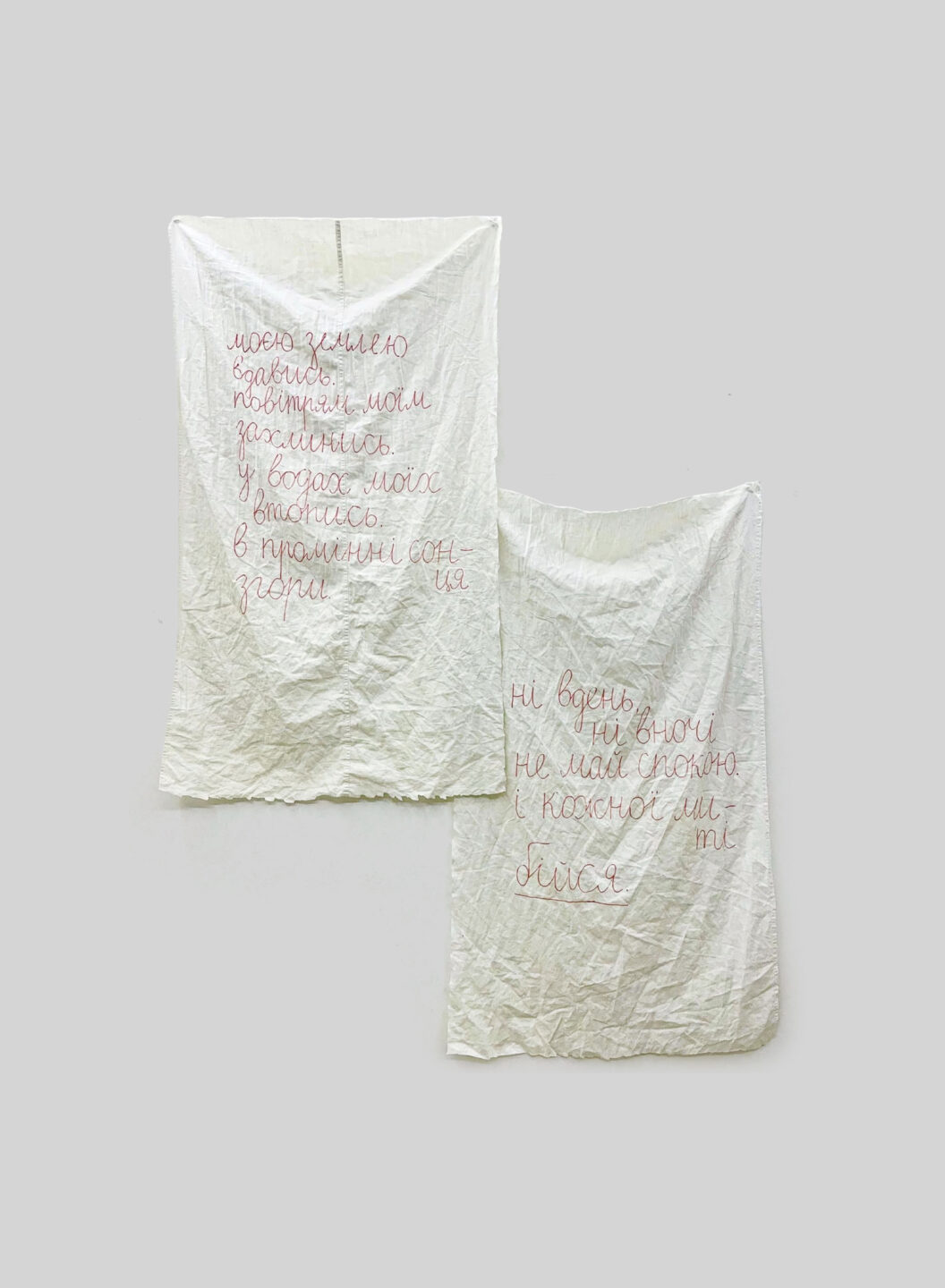 3300 Two photographs of poem-prayers written in red ink on a white linen-looking sheet.