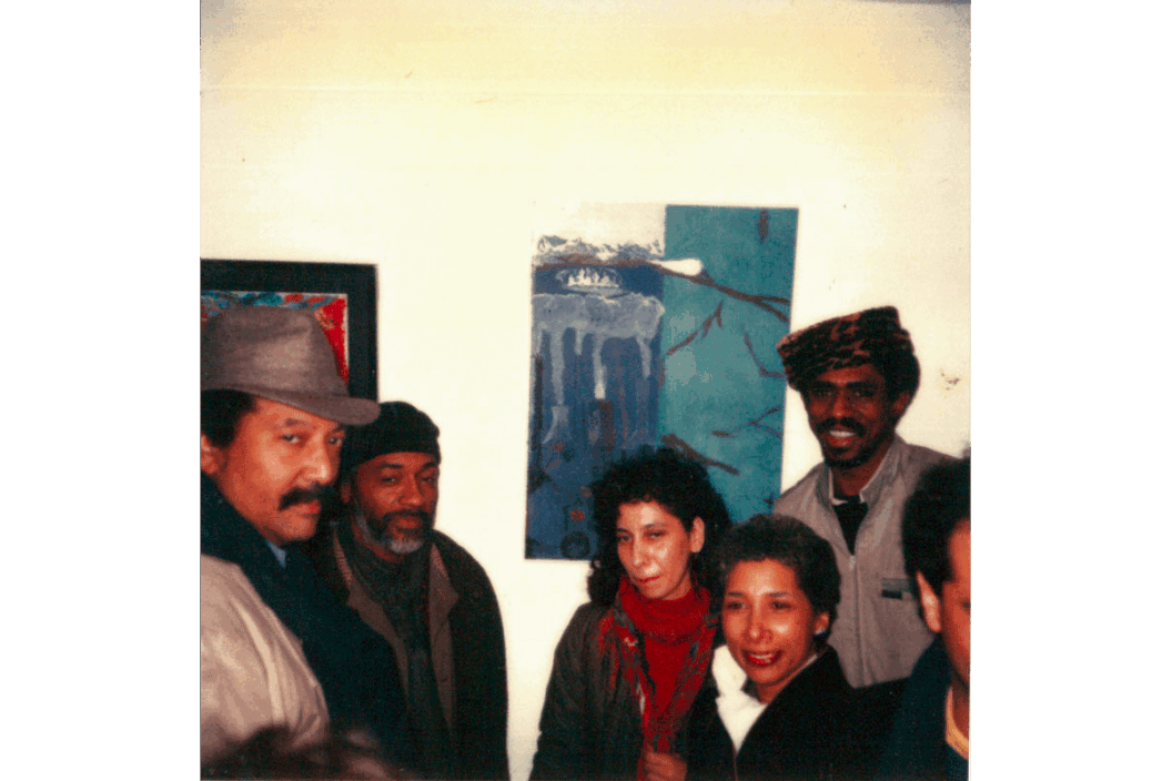 A black and white photograph of Al Loving, David Hammons, Fatima Shaik, and James Little standing in front of displayed artwork in 1984.