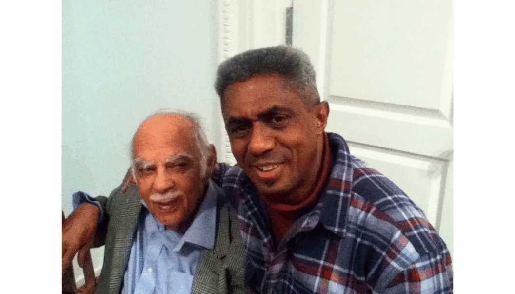 A photograph of James Little with his arm around Ed Clark in 2014, both of them smiling at the camera.