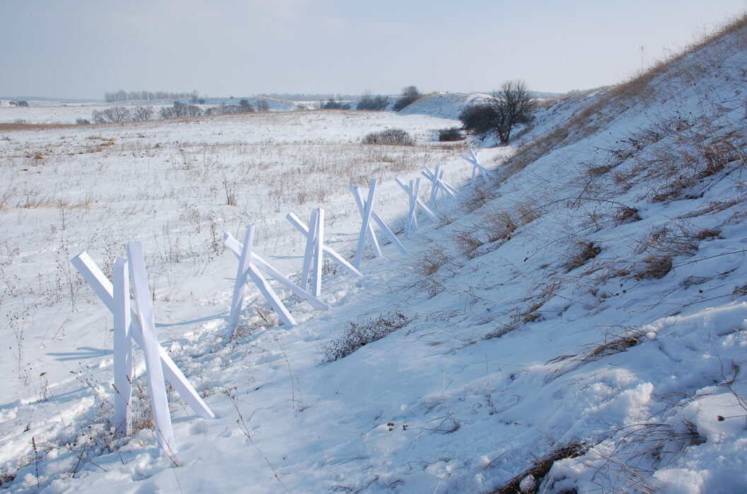 1600 A photograph of a site-specific paper sculpture of long, white rectangles propped up against each other standing at the bottom of a snowy hill.