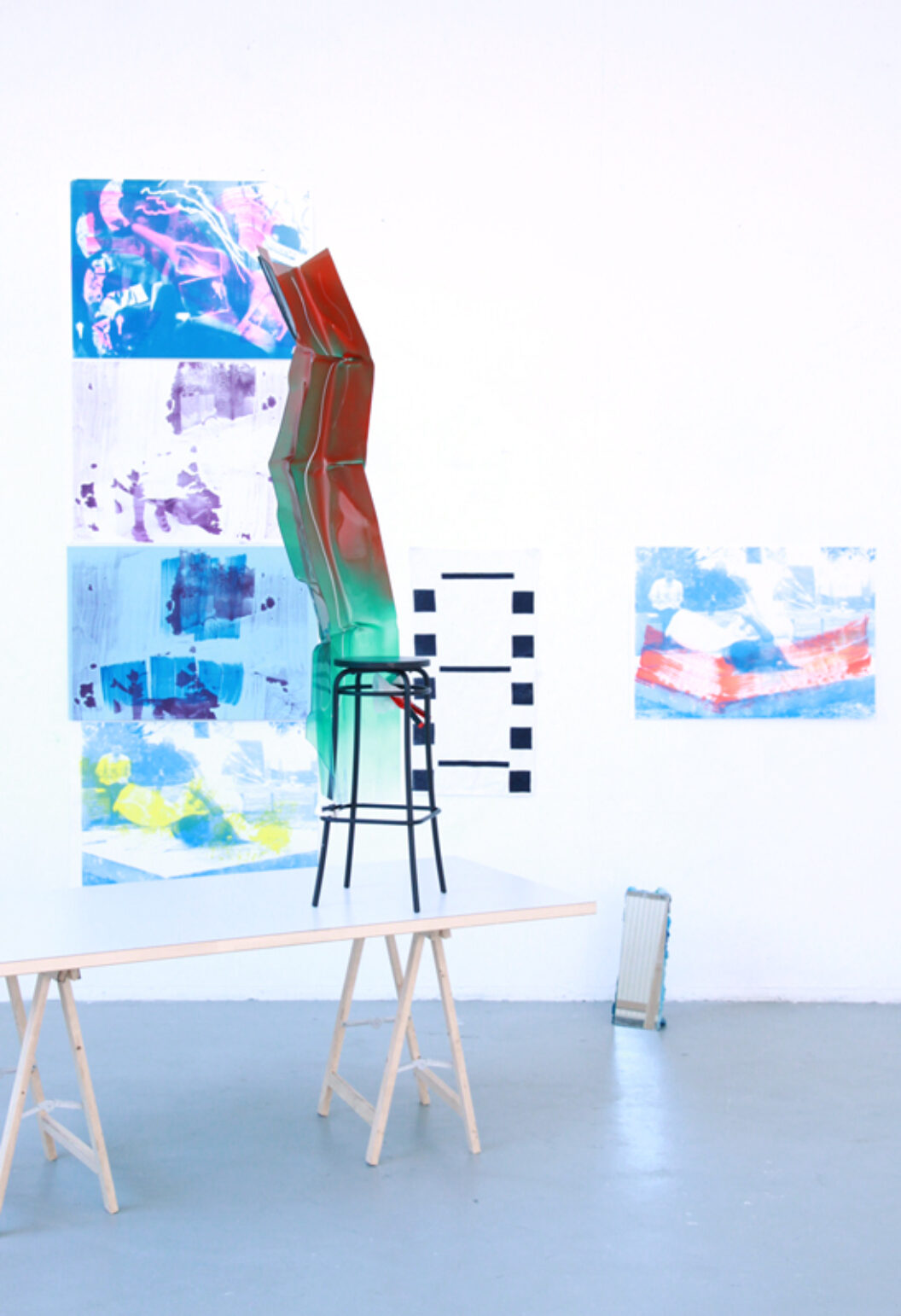 548 Screen-printed works hang on wall and a black stool stands on table