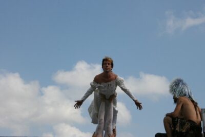Hugh Ryan in a white dress diving into a blue sky.