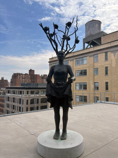 A statue situated outdoors of a Black woman with branches growing out of her head.