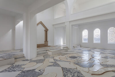 Interior view of a white, gray, and beige swirling tile work floor titled, ​Vortex (New Day Coming), by Zuzanna Czebatul