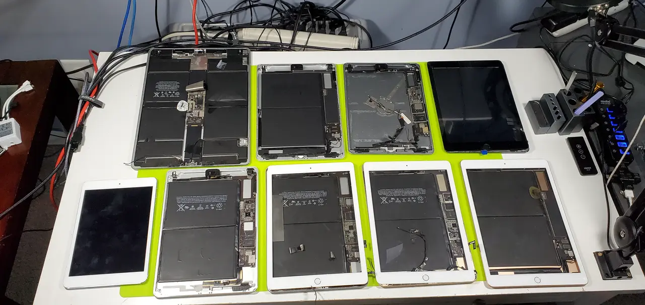 A row of iPads opened up for repair on the bench