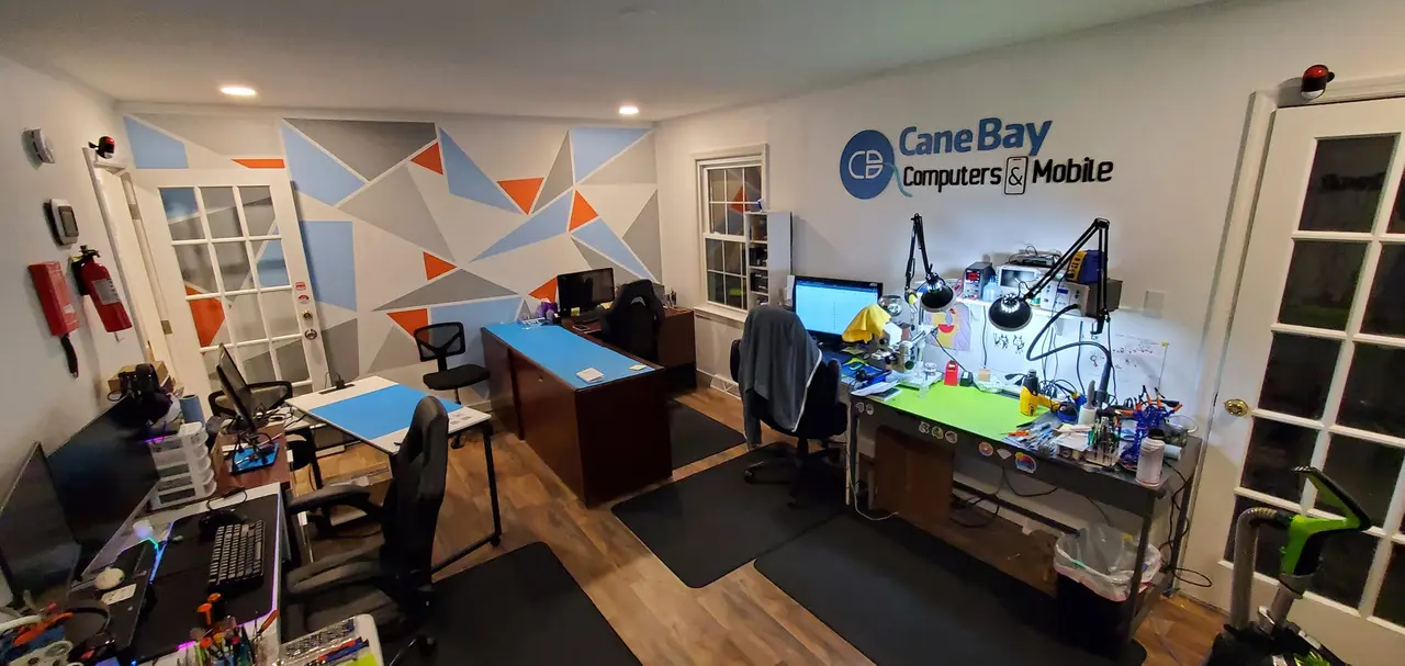 Inside the Cane Bay Computers & Mobile shop, repair benches along the wall under the Cane Bay sign