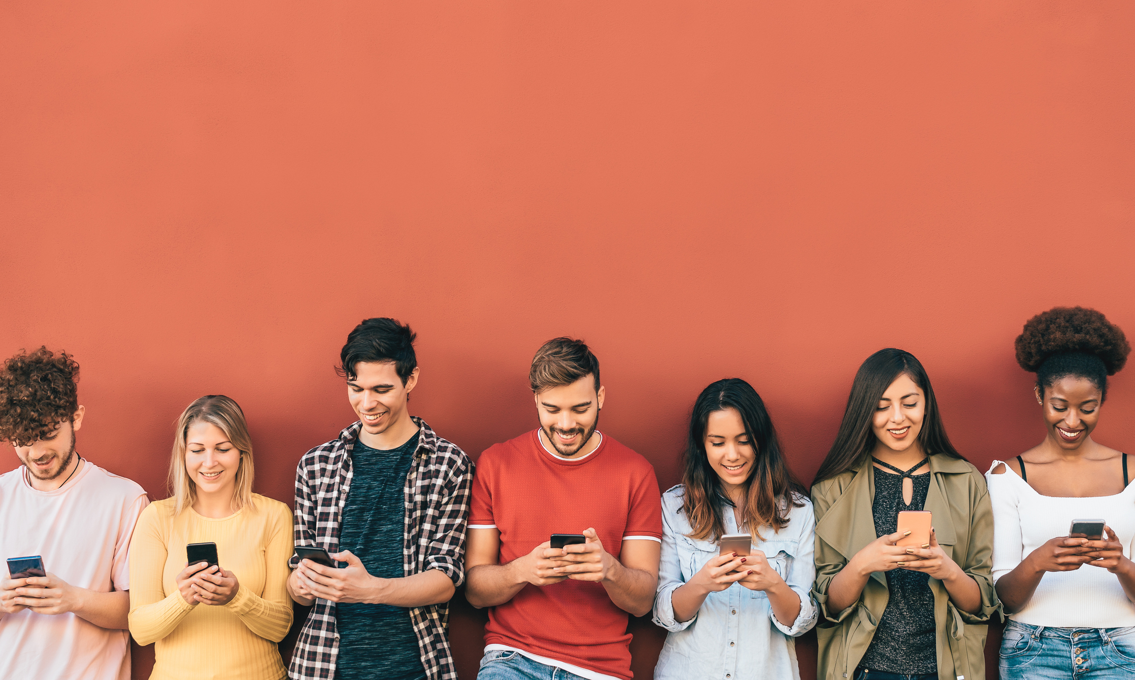 Group of young people having fun using smartphones outdoors