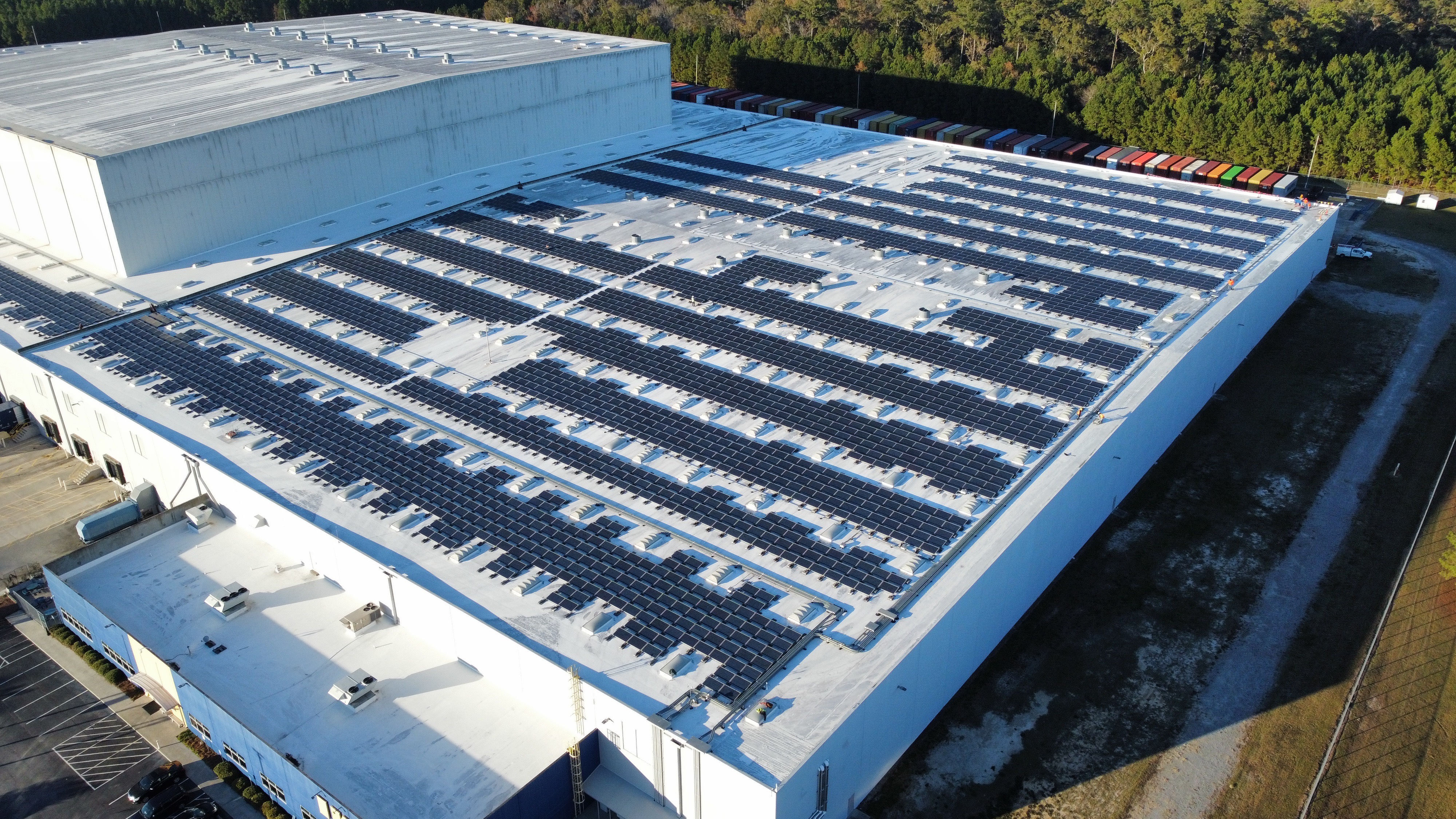 An aerial view of the roof of a modern manufacturing building that has solar panels installed on its roof.