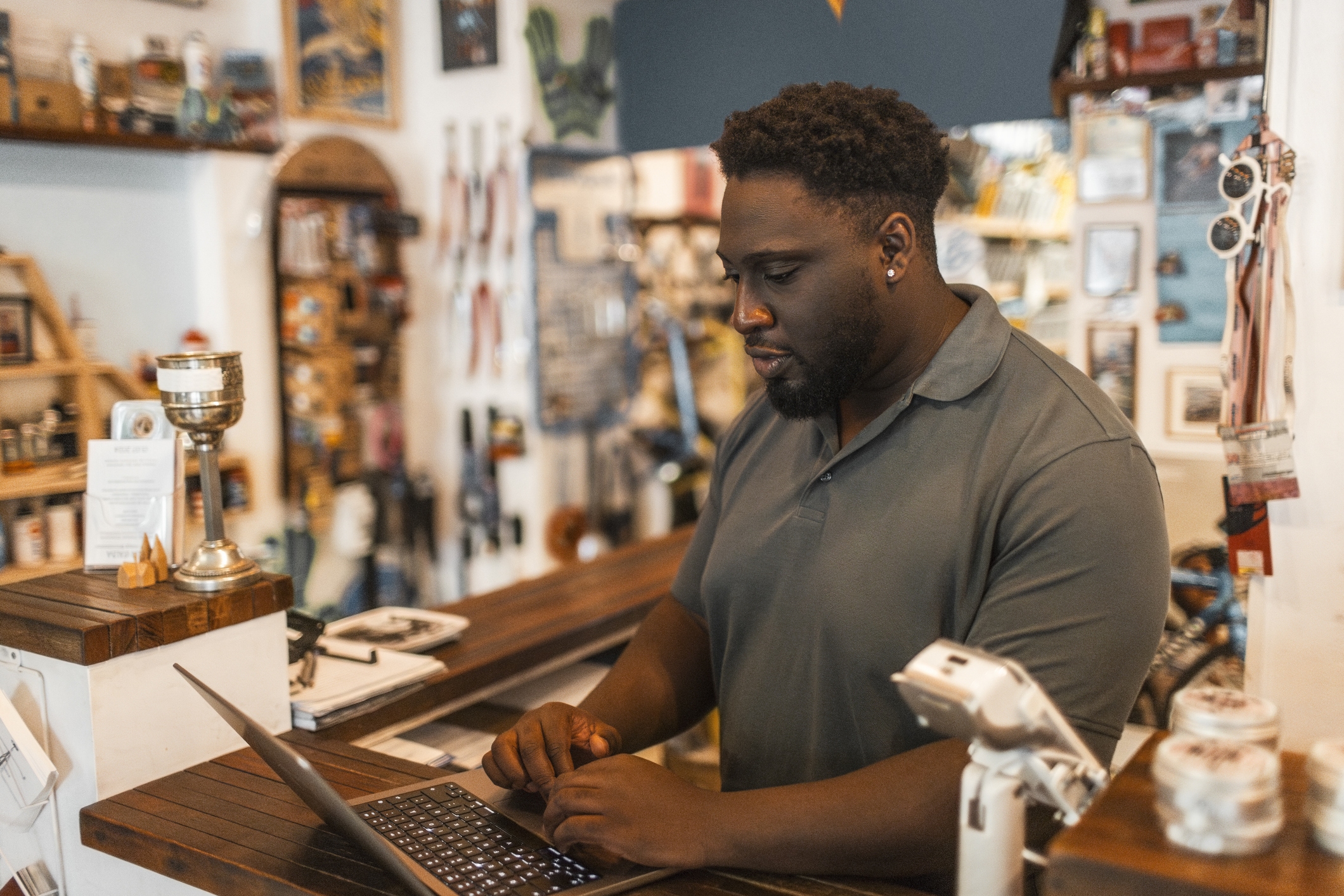 A small business owner at the counter of a bike shop on a laptop.