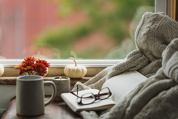 cozy nook near window with book, reading glasses, coffee mug and fall decor