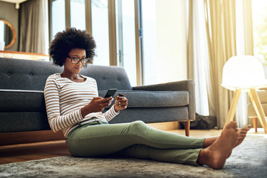  woman sitting on floor in house shopping on her phone 