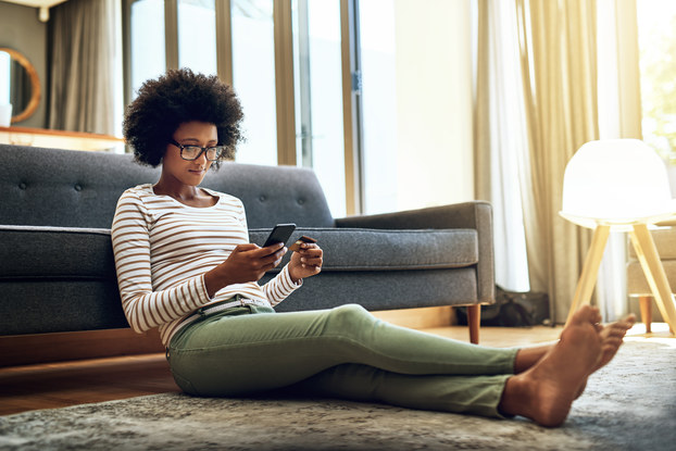 woman sitting on floor in house shopping on her phone