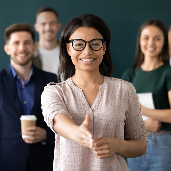woman at the forefront of a group of people with a hand out to shake hands for a job interview
