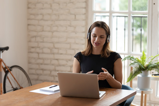 woman working on laptop and using headset at kitchen table