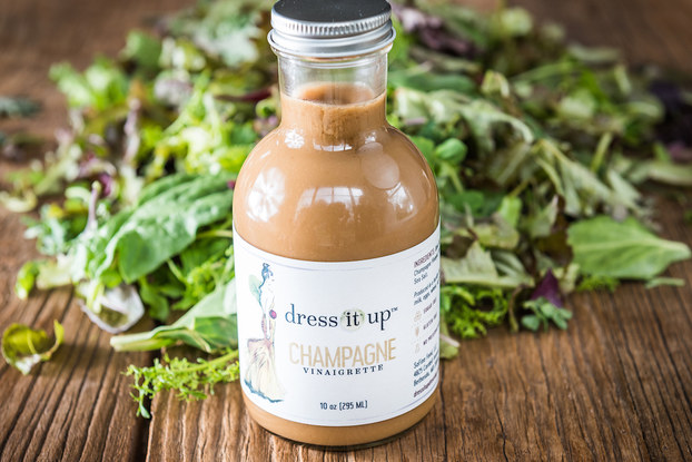 Dress It Up Dressing champagne vinaigrette on a table with a bed of greens