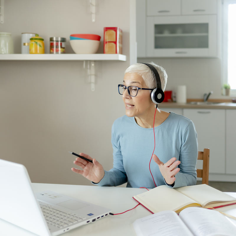 woman working from home talking on headset at dining room table