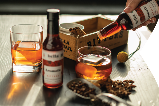 Person mixing a cocktail with Hella Cocktail Co. bitters.