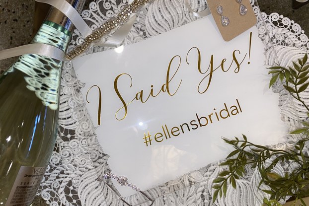 "I Said Yes!" sign with bridal earrings and a champagne bottle courtesy of Ellen's Bridal and Dress Shop.