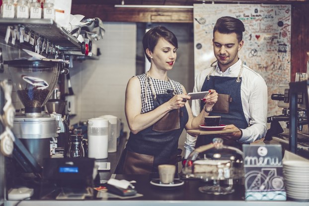 Baristas take a photo of latte art to promote cafe on social media.