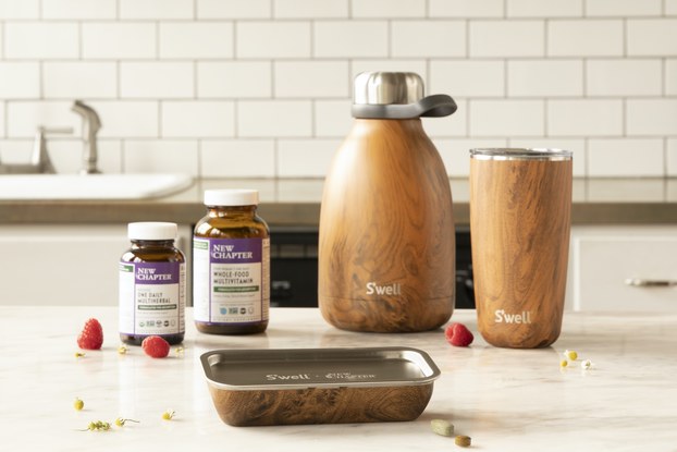 Tabletop display of S'well bottles with New Chapter vitamins and the collaborative teakwood pill case.