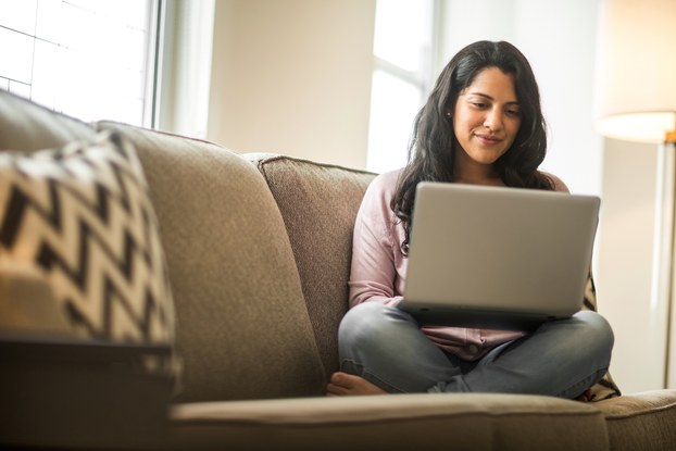 woman sitting on couch working on laptop