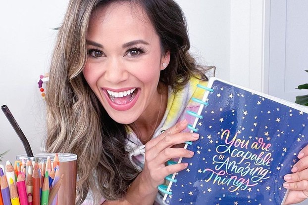 Brandi Milloy, Instagram influencer, holding a Happy Planner notebook.