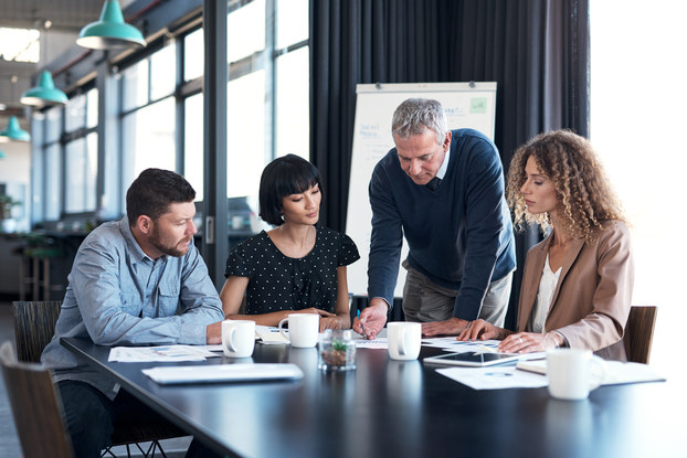 Four coworkers sitting in a meeting in a conference room.